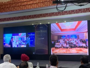 Group photo of attendees displayed on digital screen during Velocis hybrid sales conference